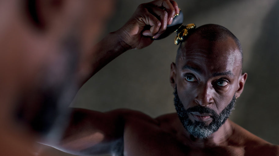 Man shaving his head with a razor in front of a mirror