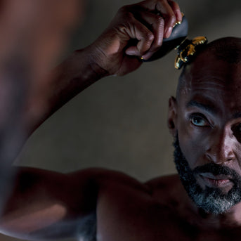 Man shaving his head with a razor in front of a mirror